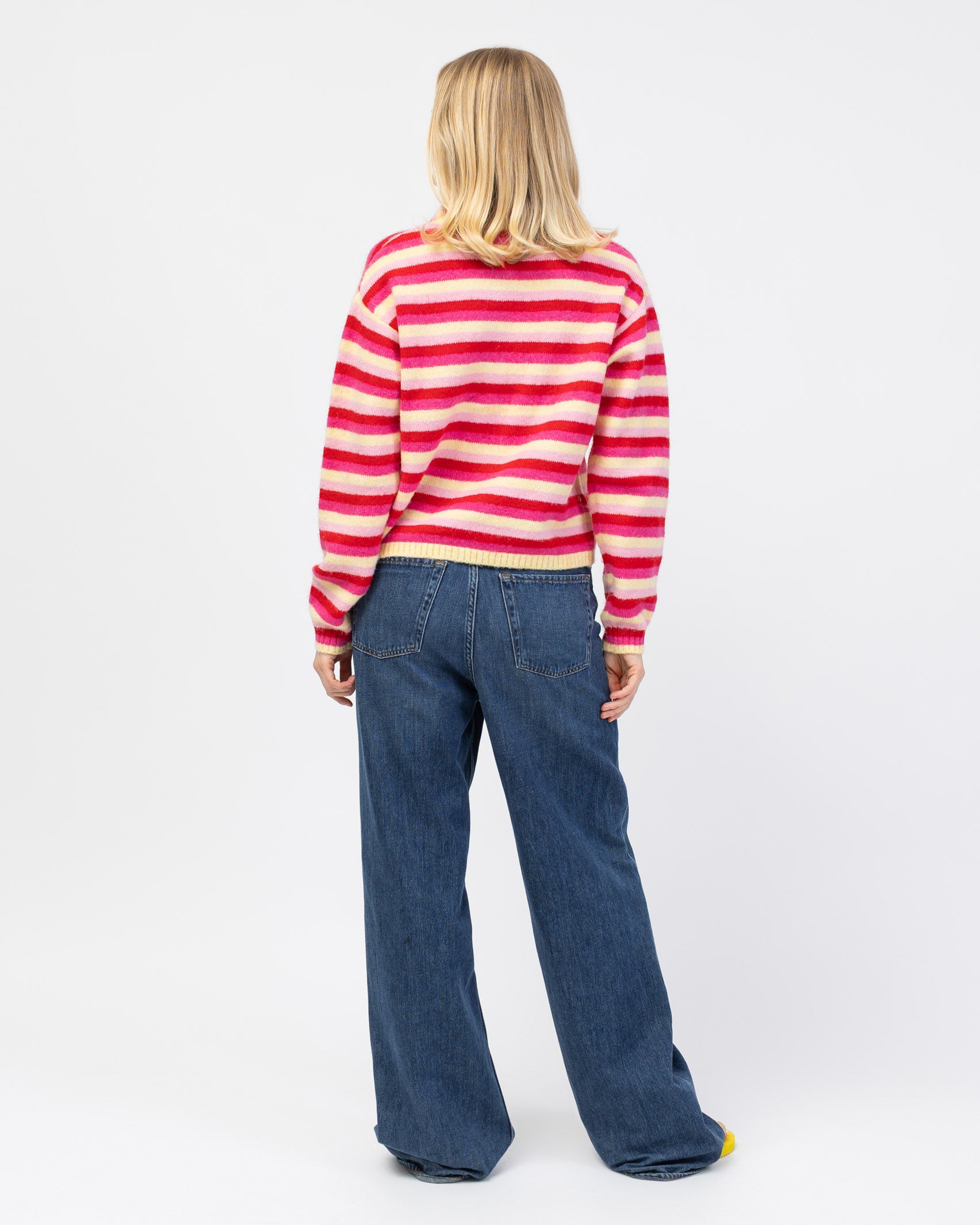 Gestreifte Strickjacke mit Rundhalsausschnitt in Kombination mit Jeans von hinten