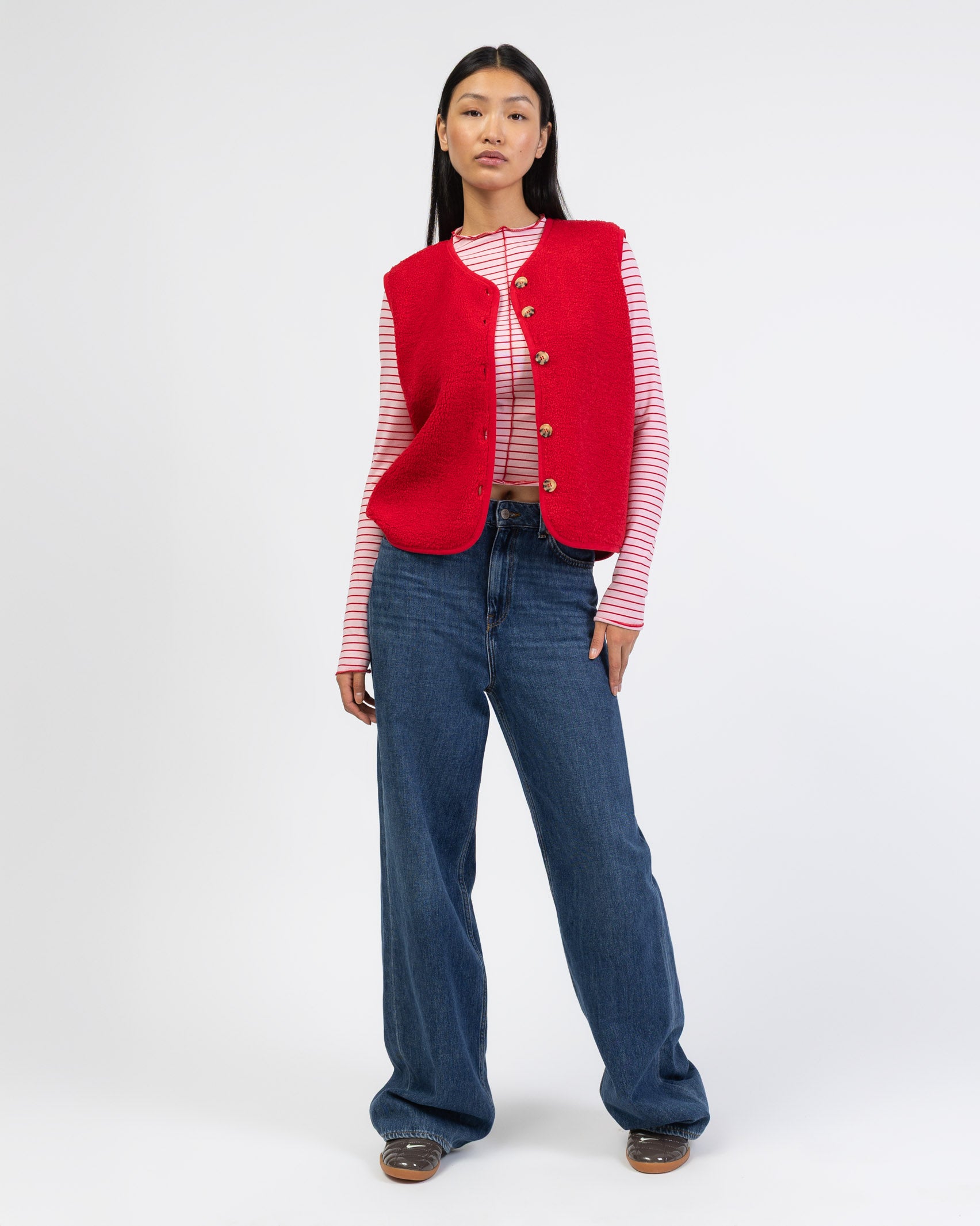 Einfarbige Teddyweste kombiniert mit Jeans und gestreifem Oberteil